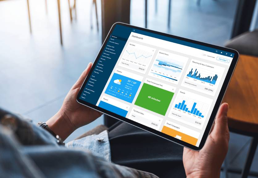 SkyTab POS A person holding an ipad with a dashboard on it.